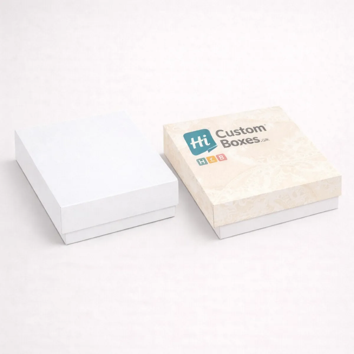 Two shallow square lidded gift boxes- one plain white and one with an elegant cream damask print- class=